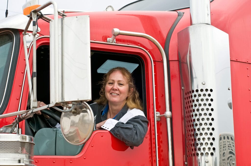 Woman truck driver leaning out the drivers side window.