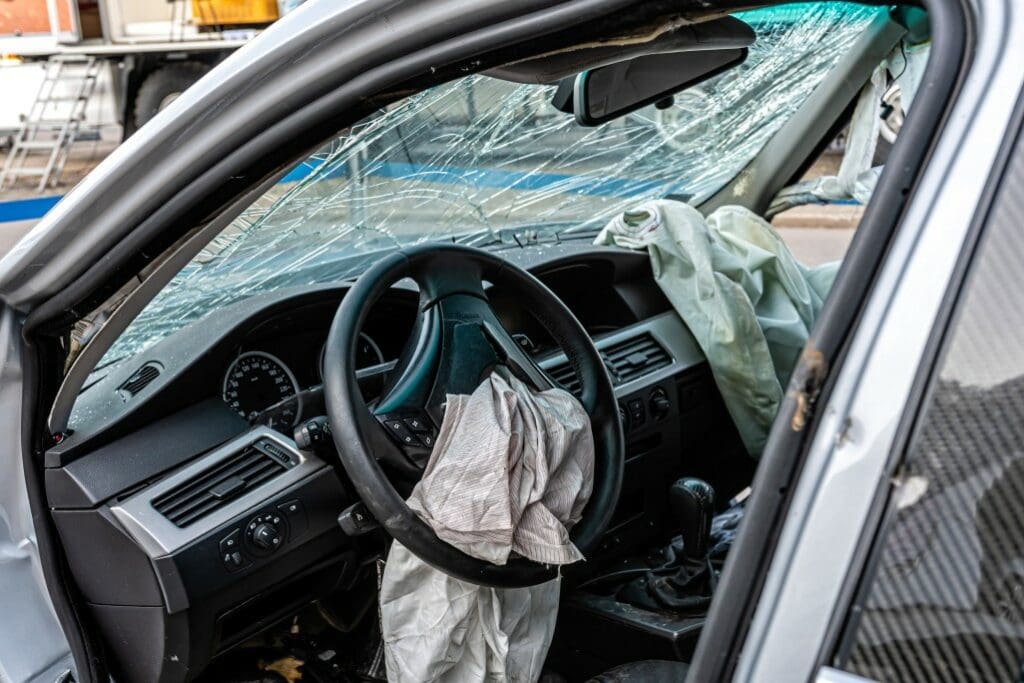 car with broken window and air bags deployed due to a lost semi truck tire